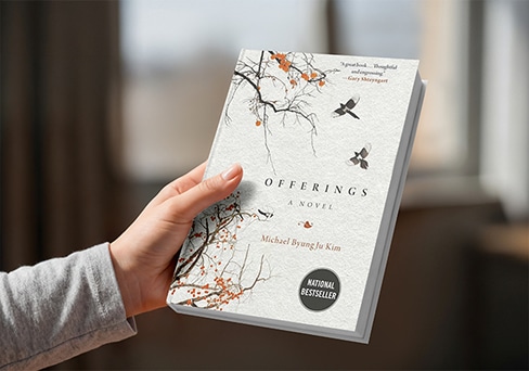 An image of someone's hand holding the Offerings A Novel book